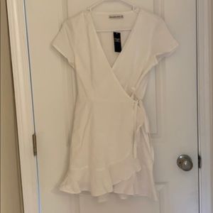 BRAND NEW! Adorable, white ruffle hem wrap dress.